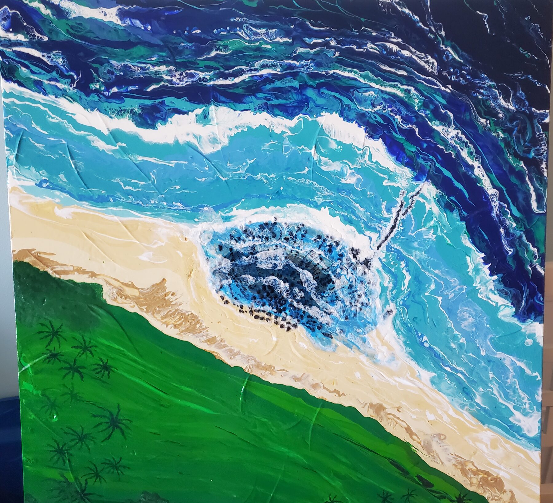 Poured turquoise water meeting a pale sand beach with a green headland above