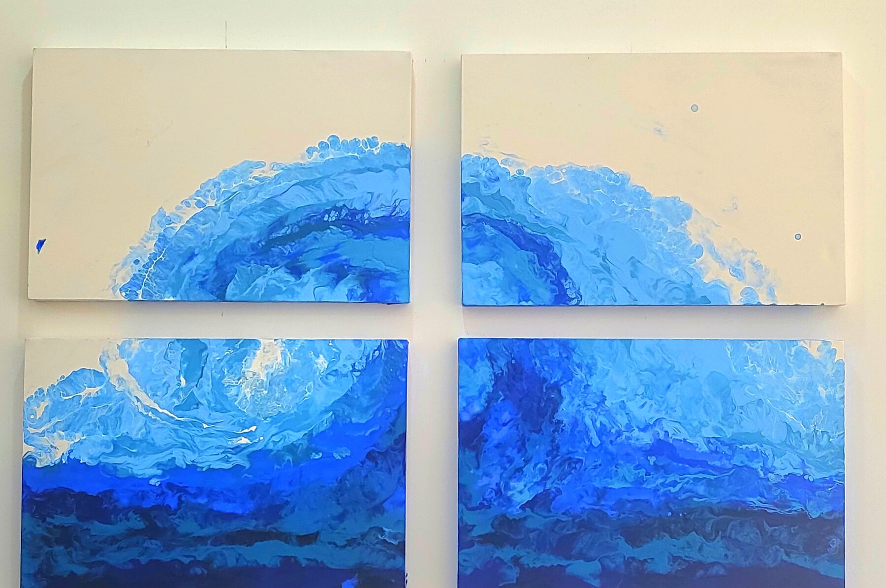 One poured blue wave carried across four separate square canvases